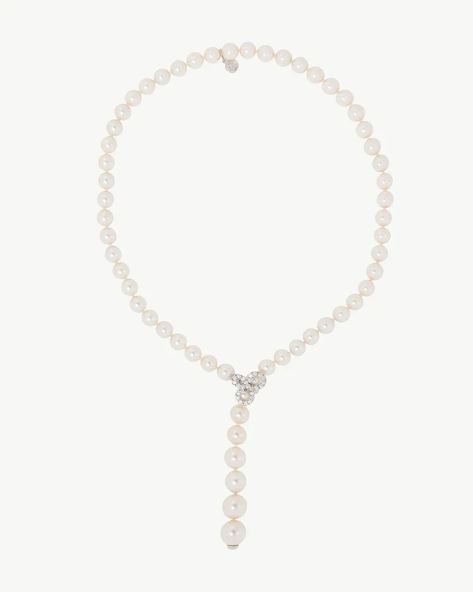 Collar de perlas blancas sobre fondo blanco, vista frontal con colgante central brillante.