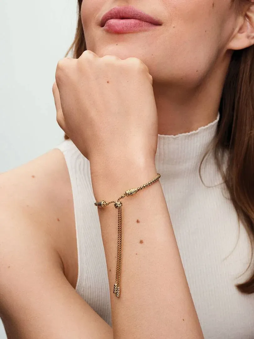 Close-up of the gold bracelet on a wrist, side view with model wearing a white turtleneck.