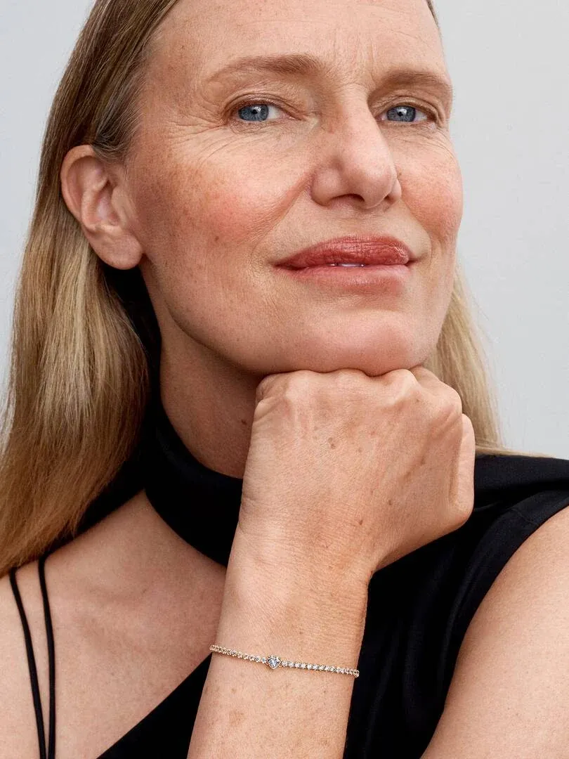 Close-up of the wrist wearing a tennis bracelet, model resting chin on hand.