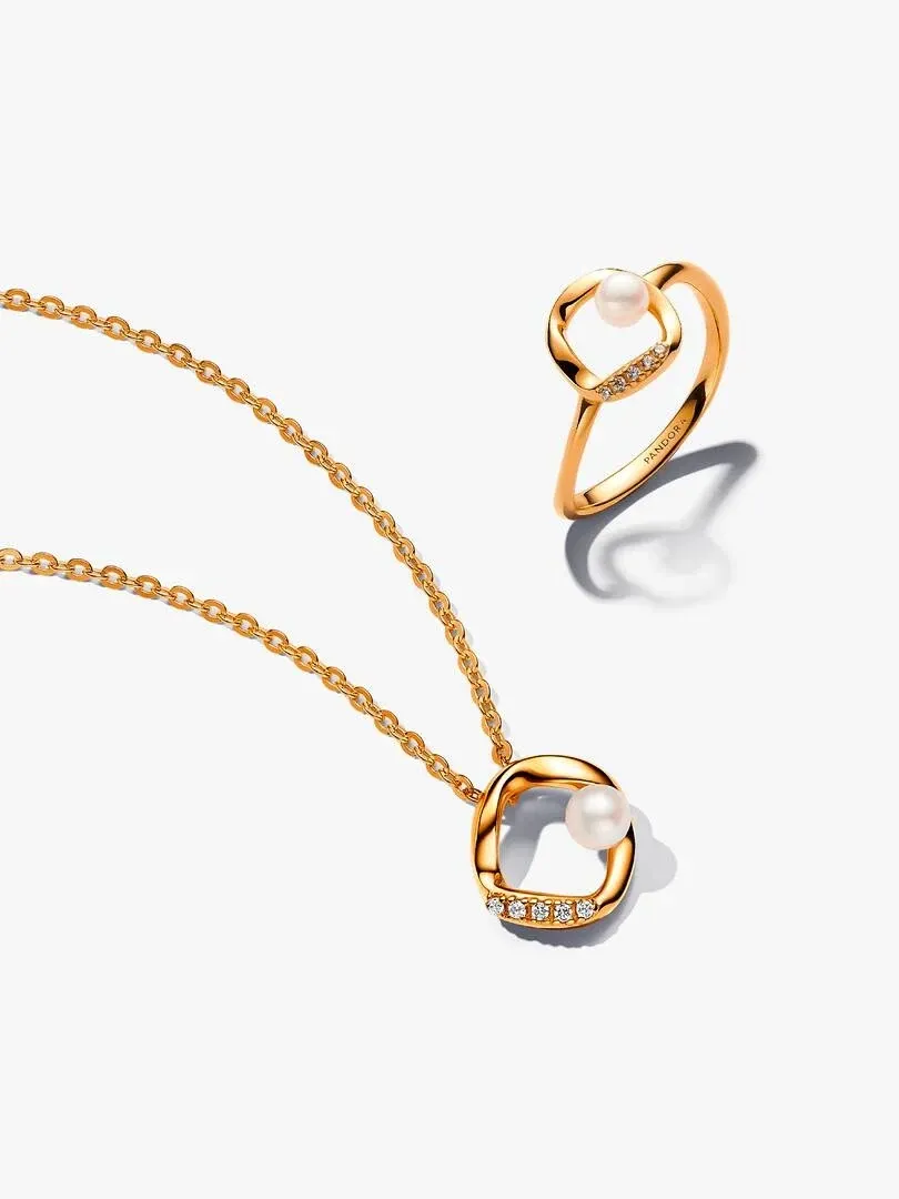 Ketting en ring met parel op witte achtergrond, bovenaanzicht met zachte schaduwen.