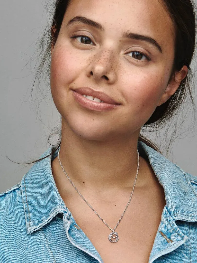 Nahaufnahme der Halskette mit drei ineinander verschlungenen Ringen an einem Model, neutraler Hintergrund.