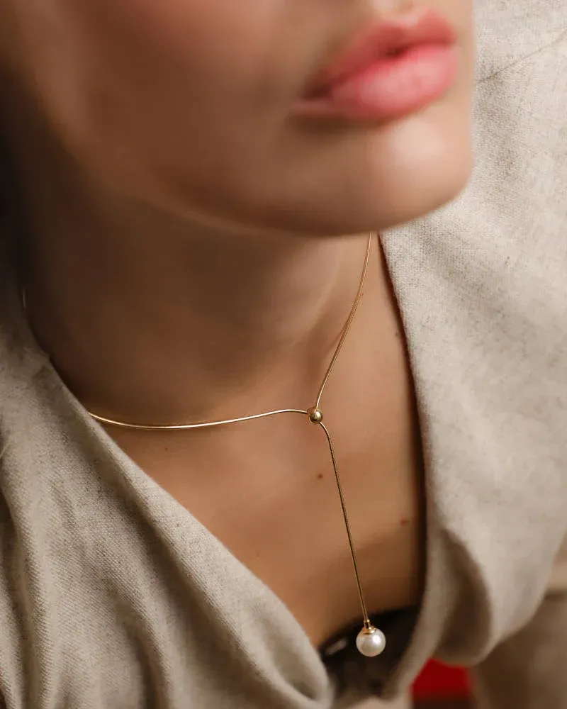 Gros plan du collier avec perle sur le cou d'un mannequin, vue de face avec fond flou.