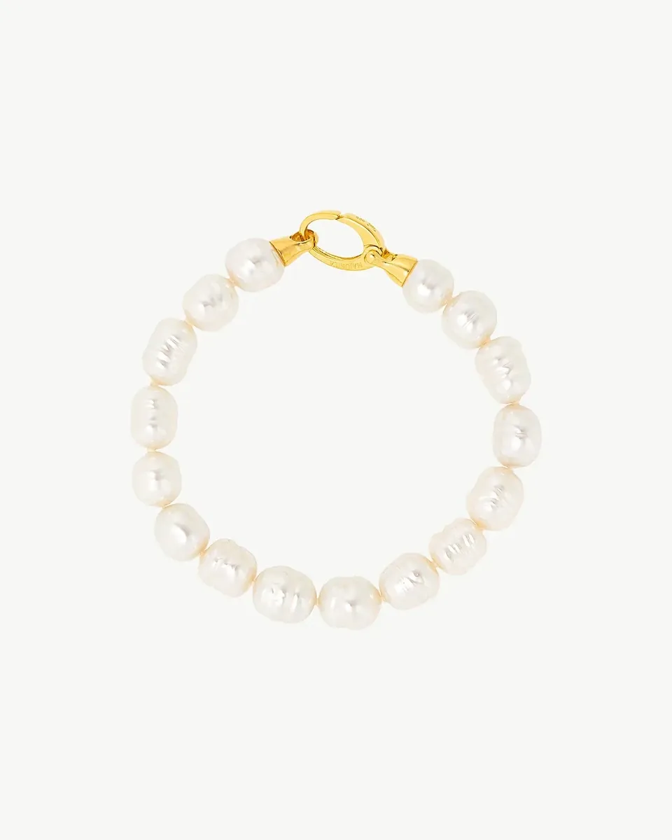 Top view of a bracelet arranged in a circle on a white background, detail of the gold clasp.