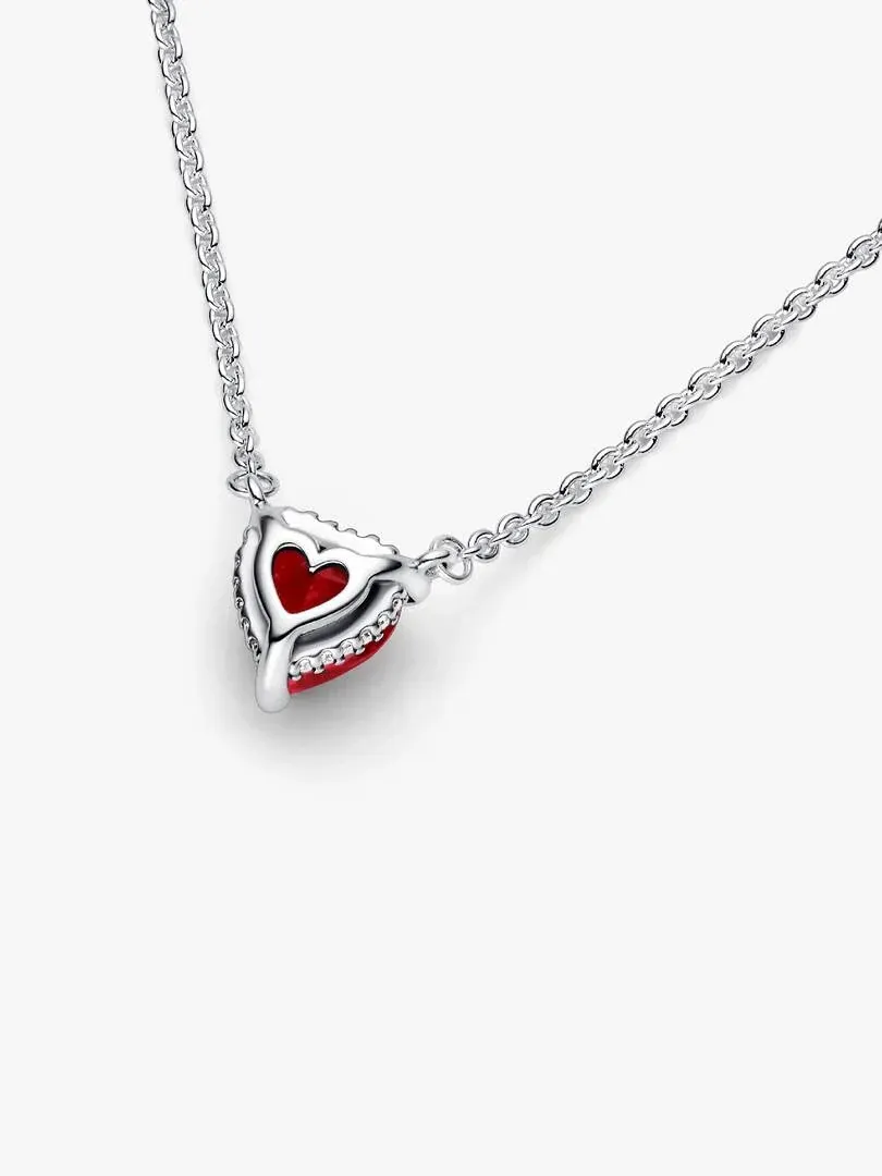Heart pendant necklace with red stone on white background, diagonal angle shot.
