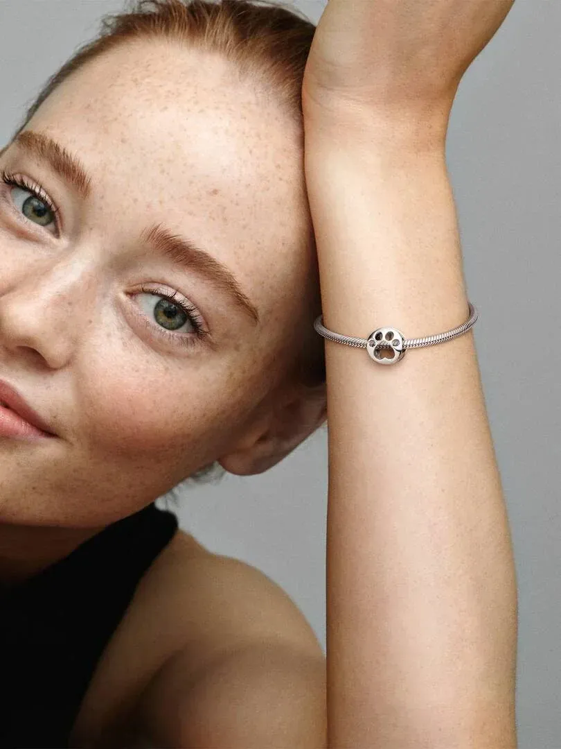 Close-up of the wrist wearing the dog paw charm, side view against a neutral gray background.