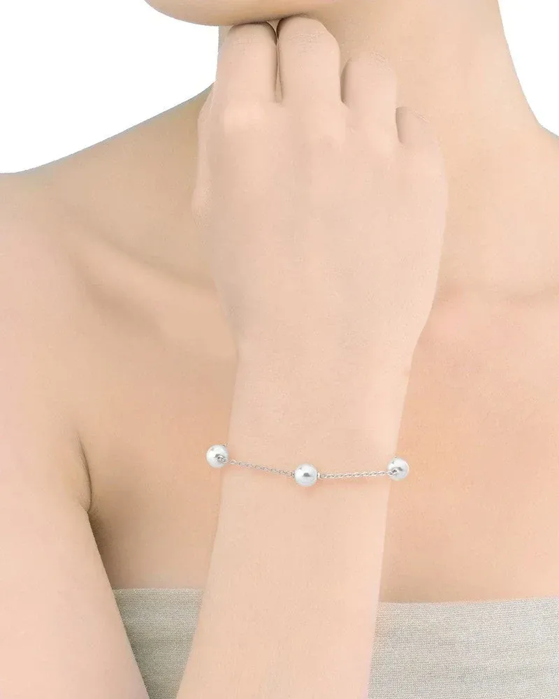 Primer plano de la pulsera con perlas blancas en la muñeca, toma lateral sobre piel.