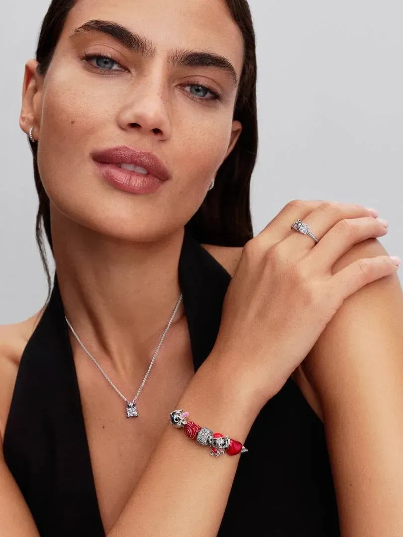 Modelo con collar y pulsera, toma de plano medio sobre fondo gris neutro.