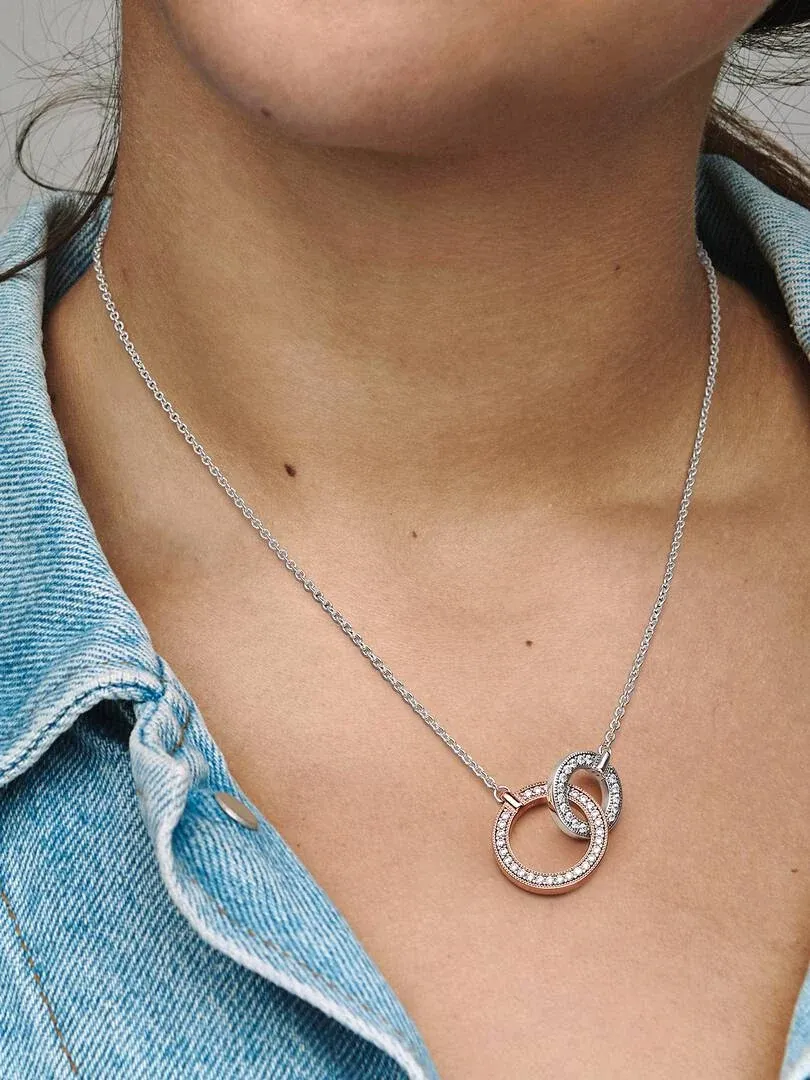 Close-up of the interlocking circles necklace worn on a neck with blue denim clothing.