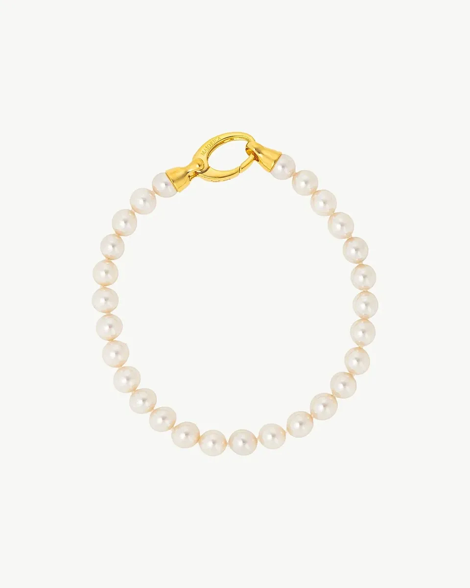 Pearl bracelet arranged in a circle on a white background, top view with gold clasp detail.