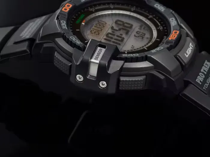 Primer plano lateral del reloj, enfocando el botón 'SENSOR' sobre fondo negro.