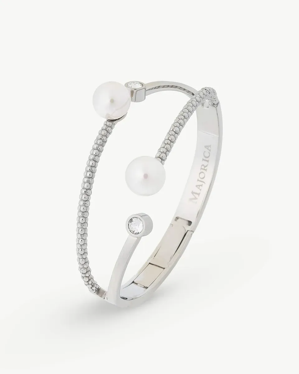 Vista en perspectiva de brazalete rígido con perlas y circonitas sobre fondo blanco