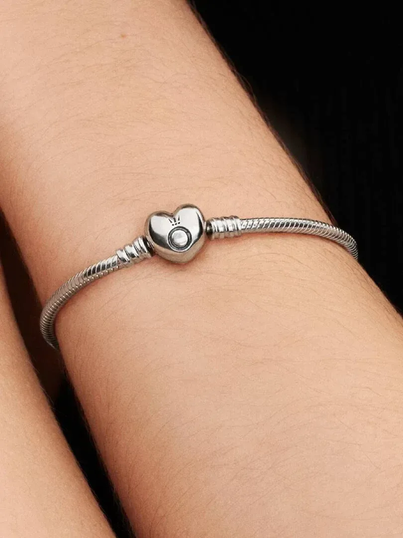 Close-up of the silver snake chain bracelet with heart clasp worn on a wrist, side view.