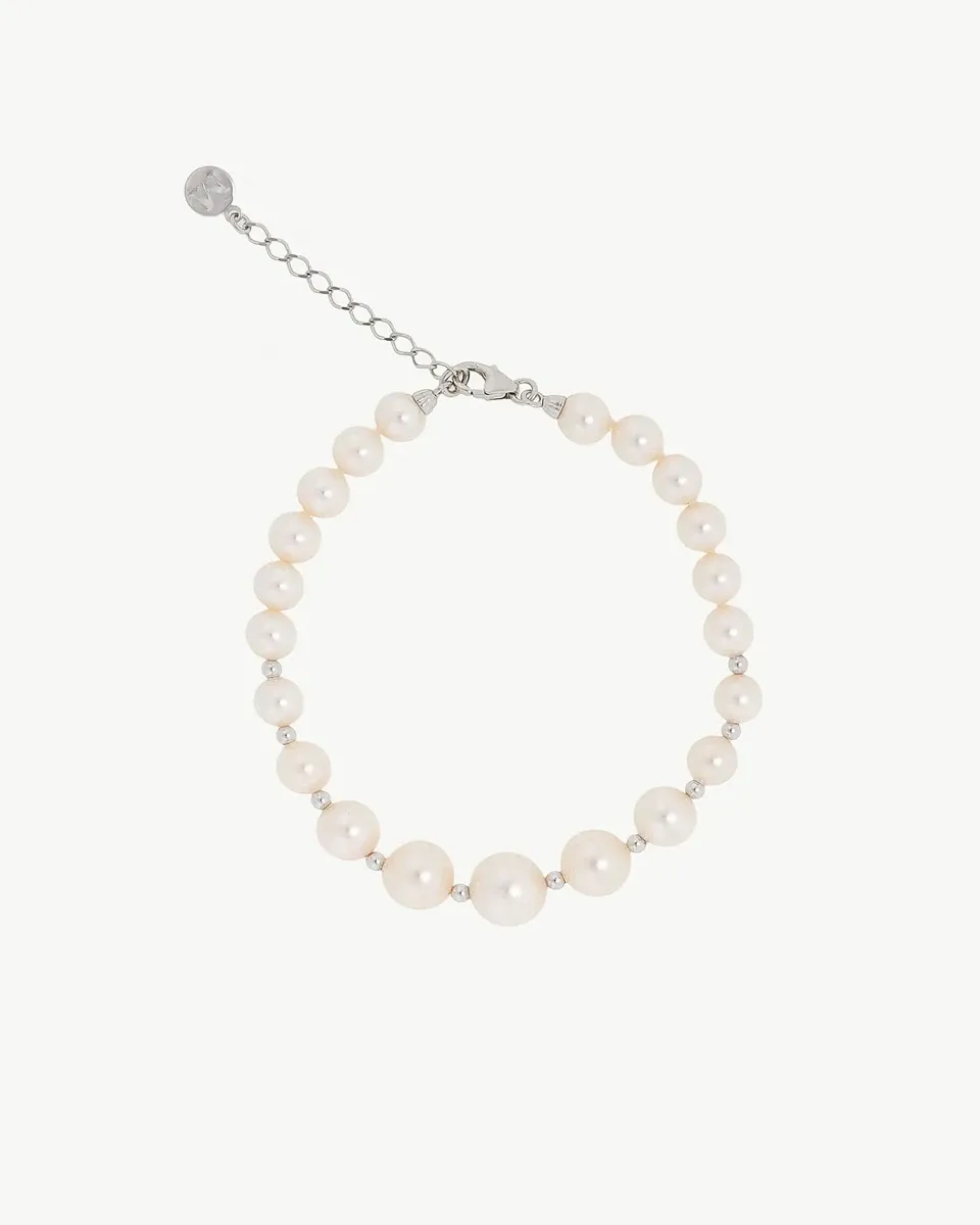 Vista cenital de pulsera de perlas dispuesta en círculo sobre fondo blanco, incluyendo el cierre de cadena de plata