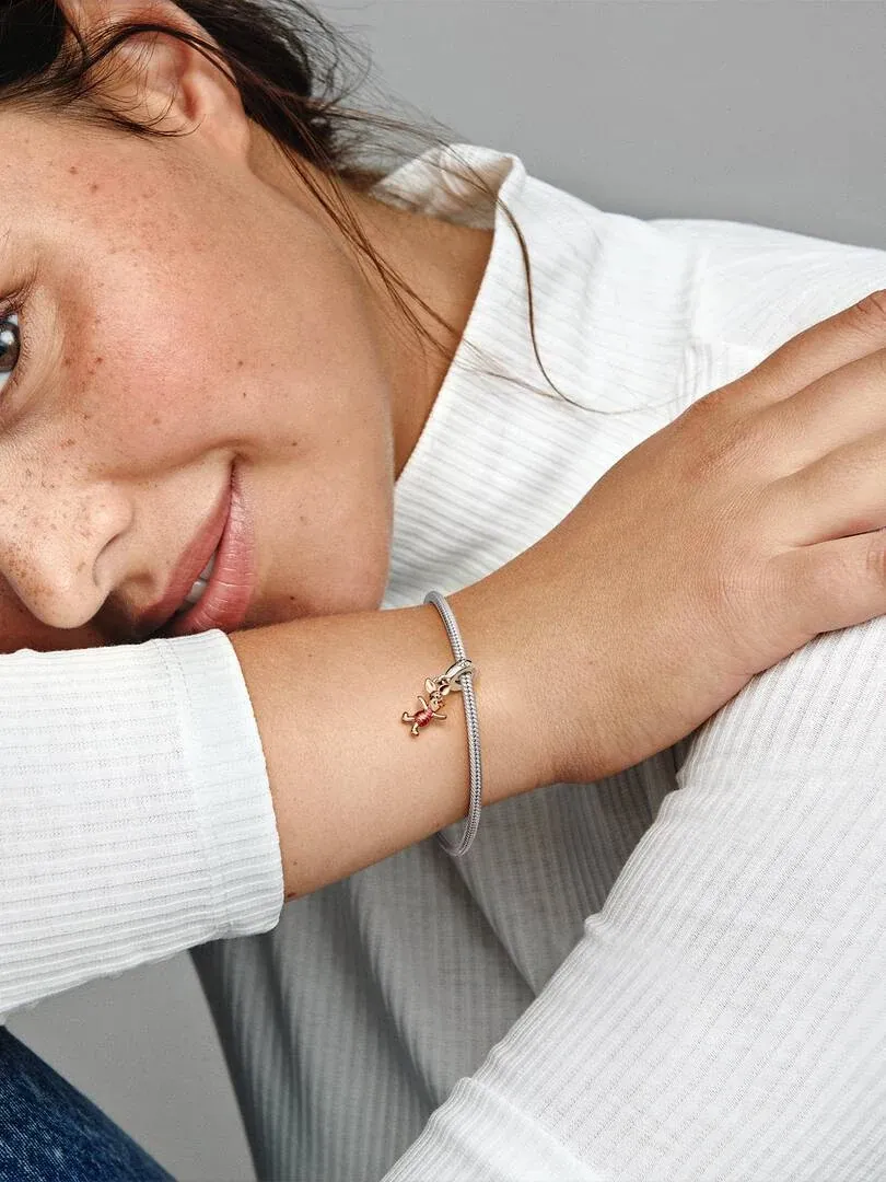 Nahaufnahme des Piglet-Charms am Handgelenk, Seitenansicht mit Modell in weißem Oberteil.