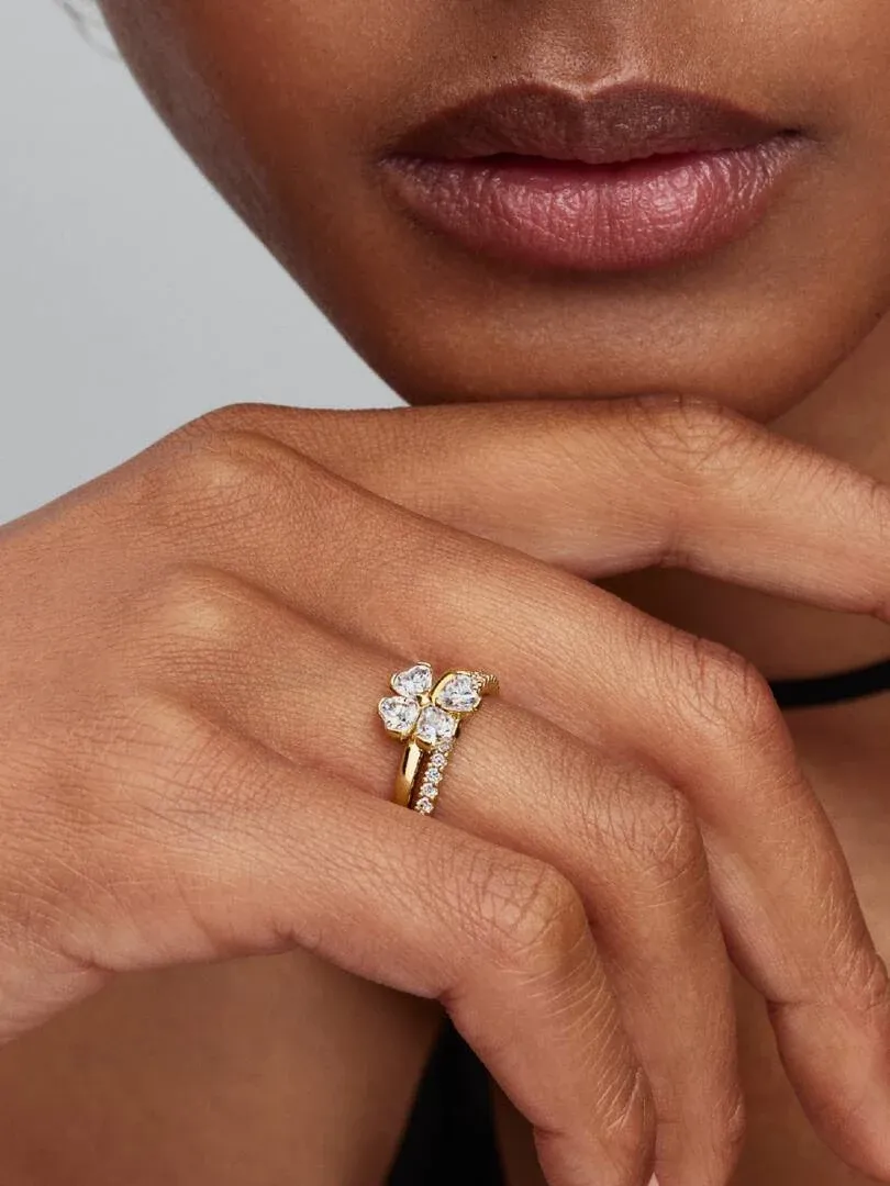 Close-up van twee gouden ringen met zirkonia's om een vinger, zijaanzicht op de huid.
