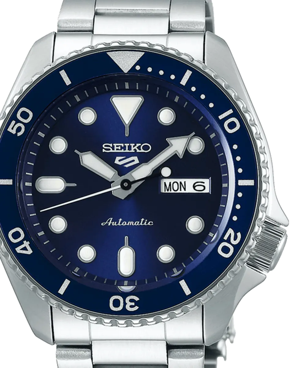 Gros plan du cadran bleu, de la lunette tournante et de la couronne de la montre, fond blanc.
