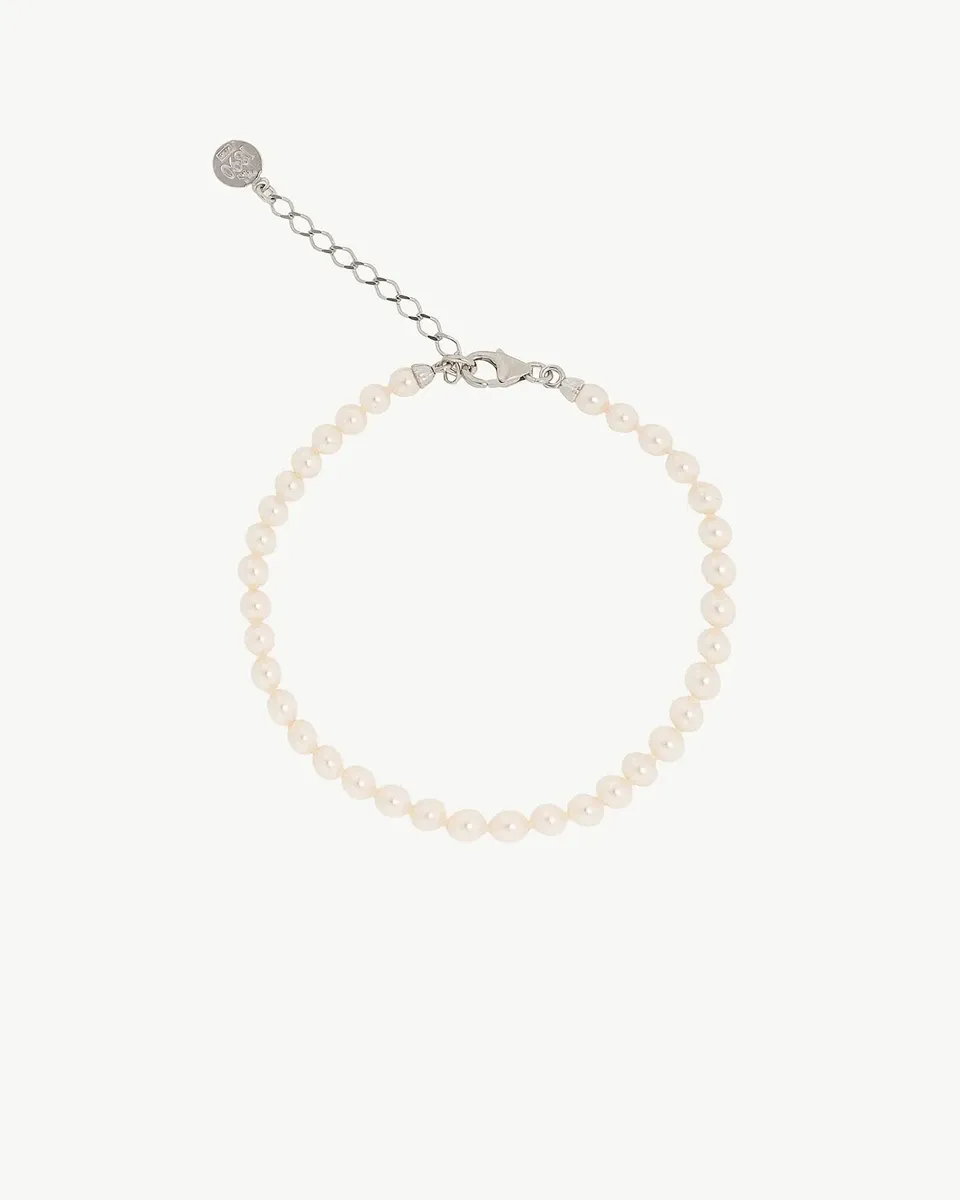 Bracelet en perles disposé en cercle sur fond blanc, vue de dessus avec détail du fermoir et de la chaîne d'extension.