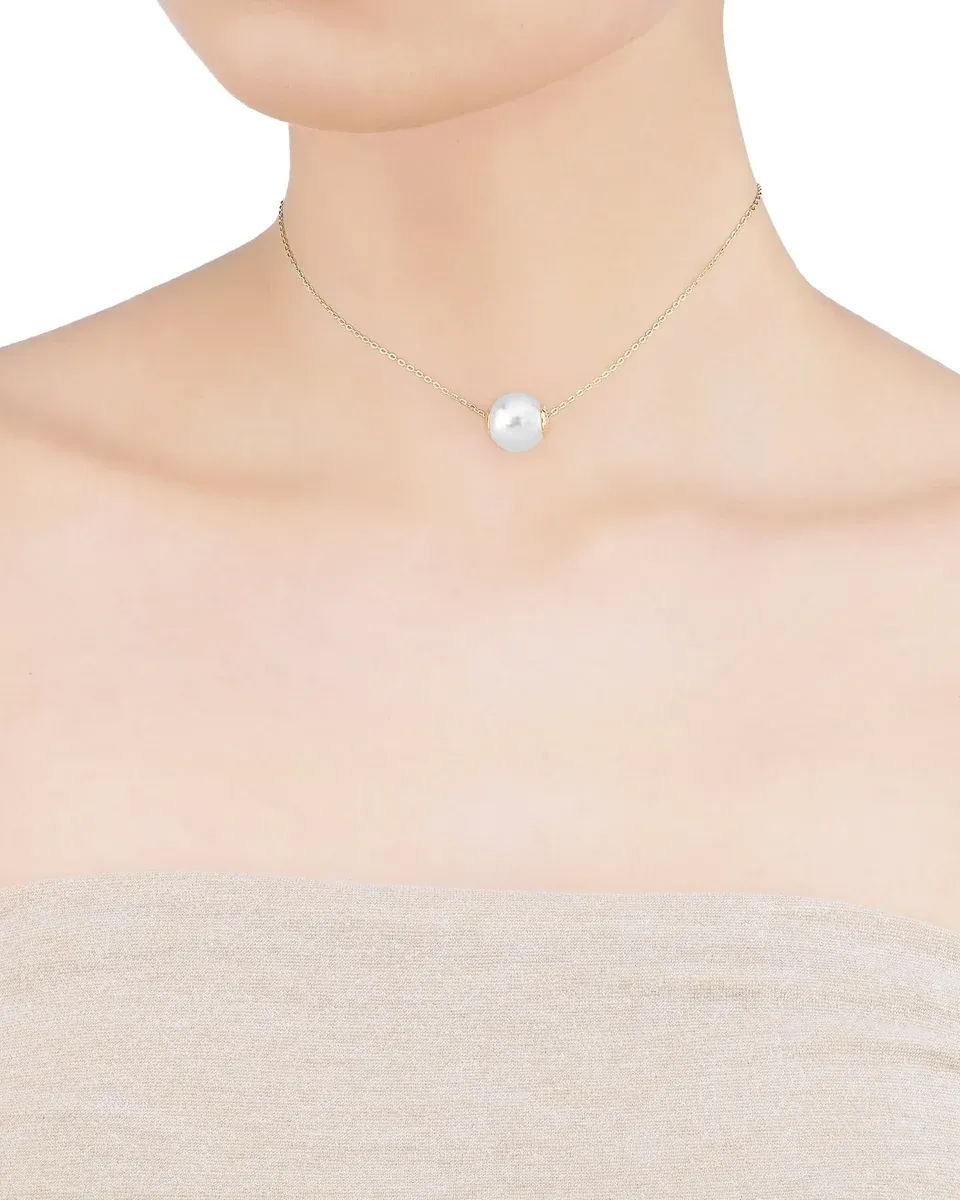 Primer plano de gargantilla con perla blanca sobre el cuello de una modelo, toma frontal centrada.