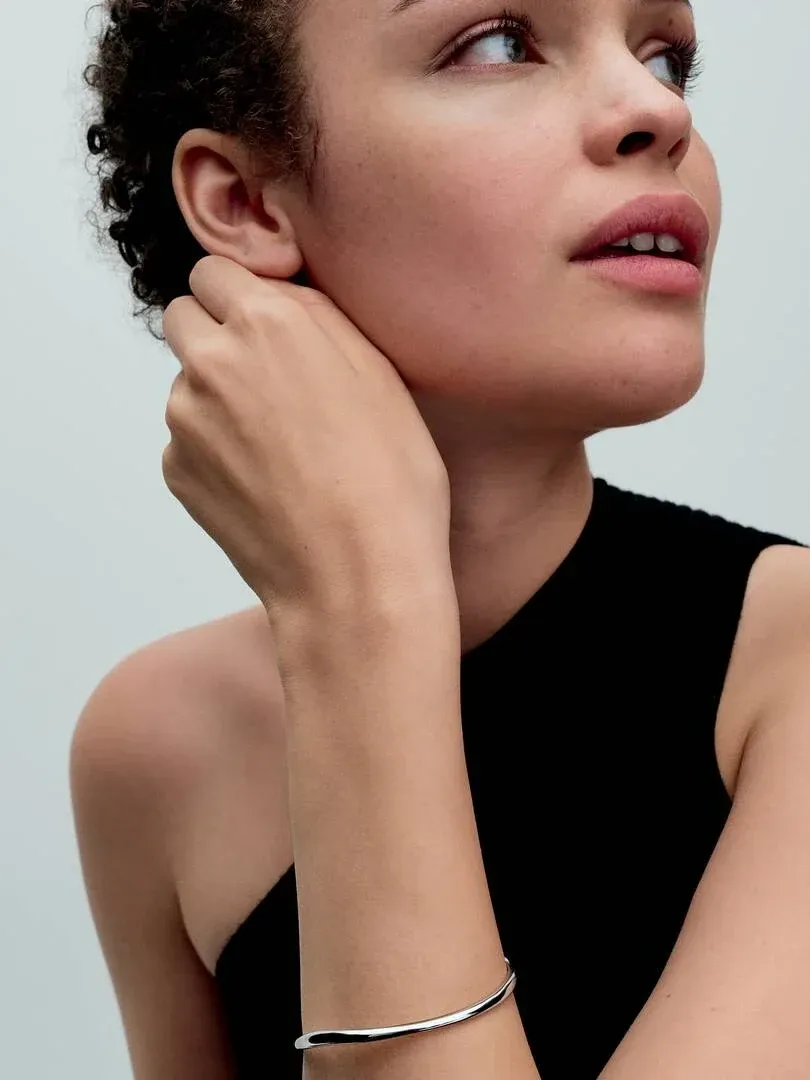 Close-up of bangle on wrist, side view with model against a neutral grey background.