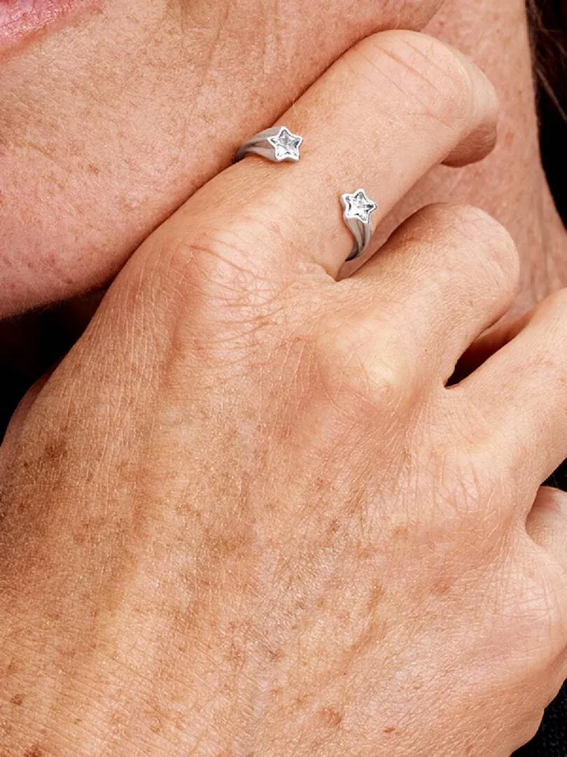 Close-up van de open sterrenring in zilver gedragen aan een vinger, zijaanzicht.