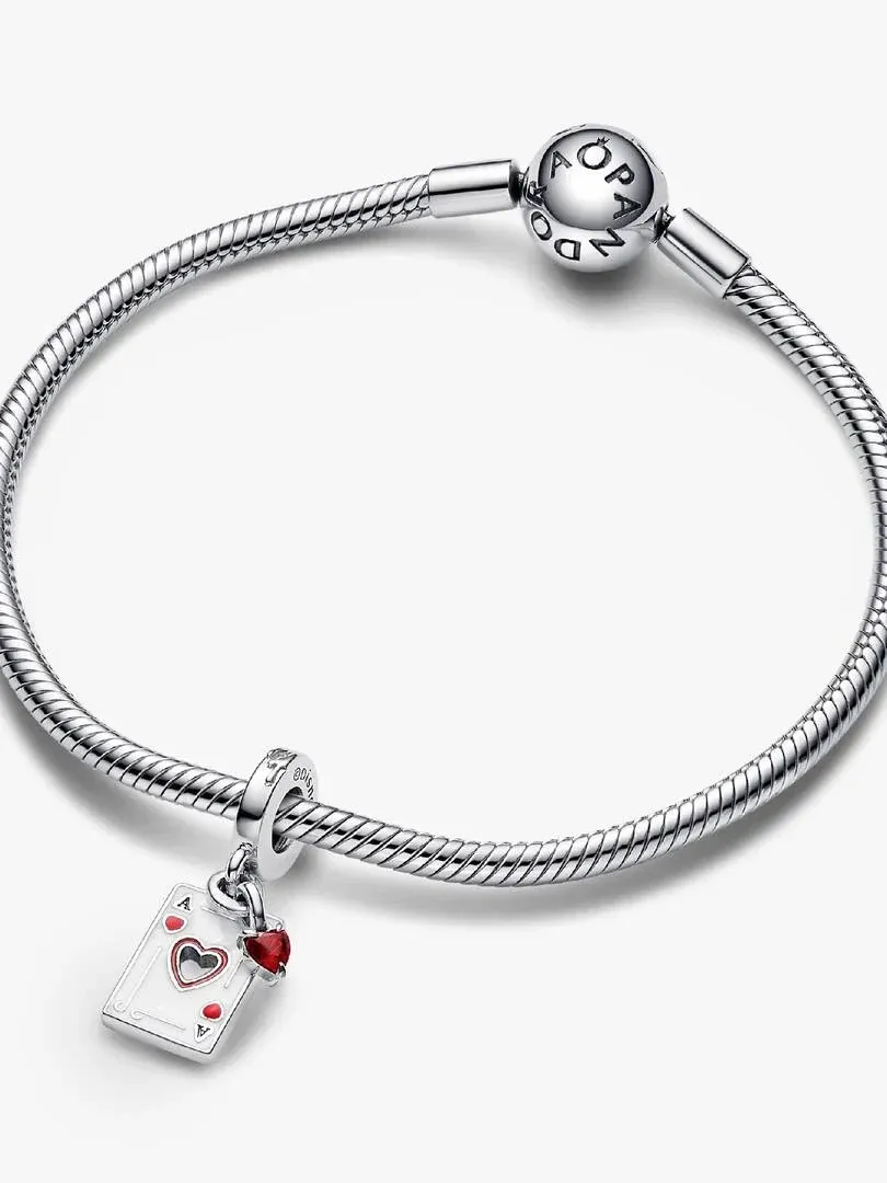Playing card charm hanging from a silver snake chain bracelet, side view on white background.