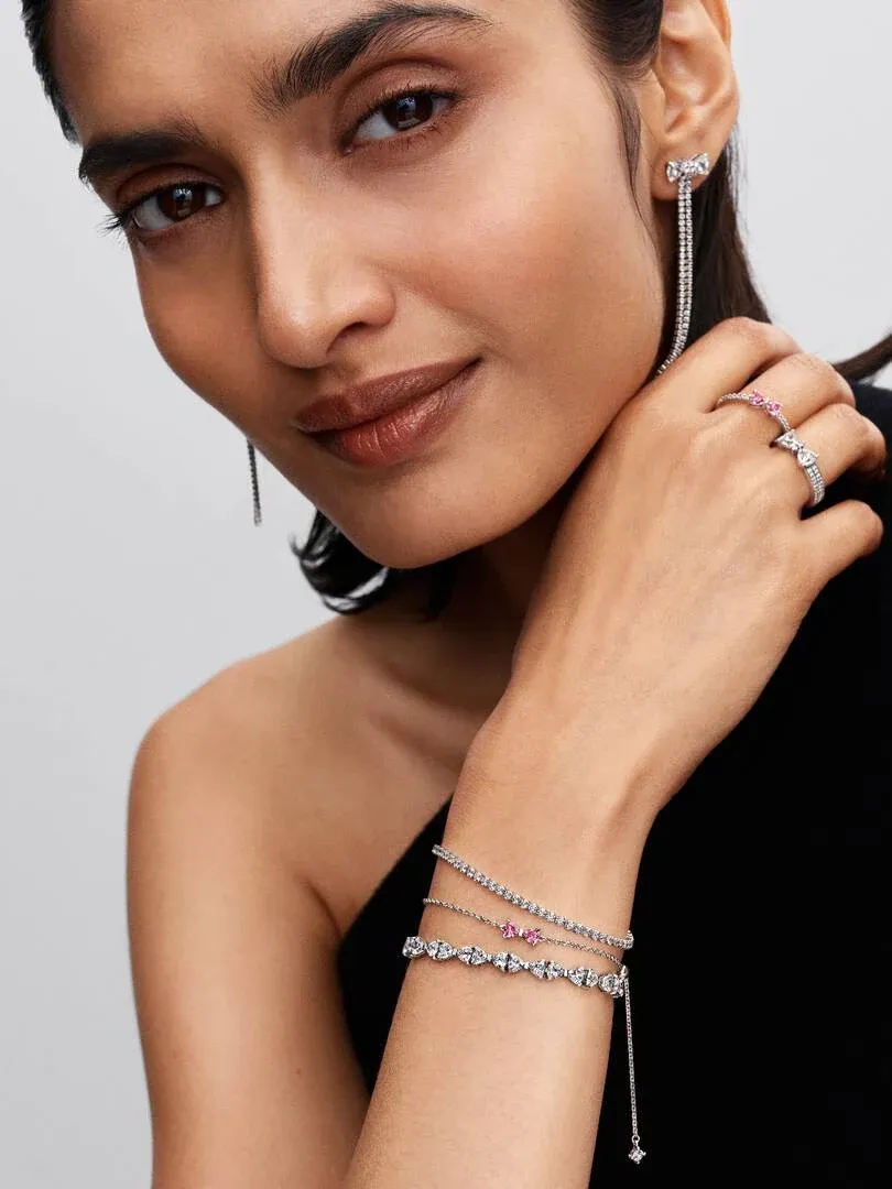 Gros plan du poignet avec bracelet chaîne et bague, modèle sur fond neutre.