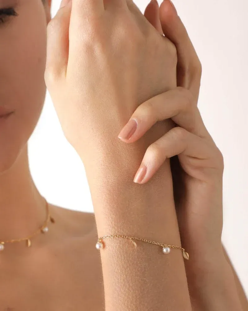 Gros plan du bracelet doré avec perles au poignet, vue de profil sur peau douce.