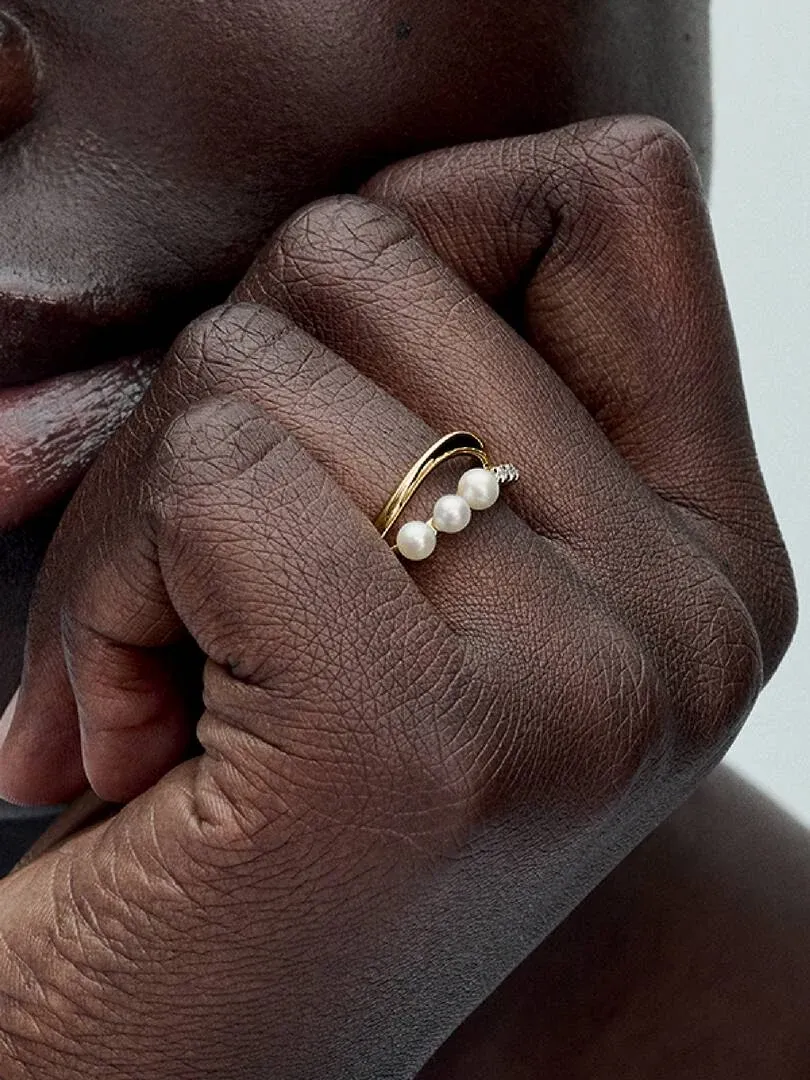 Close-up of the double band pearl ring worn on a finger, side view against skin.