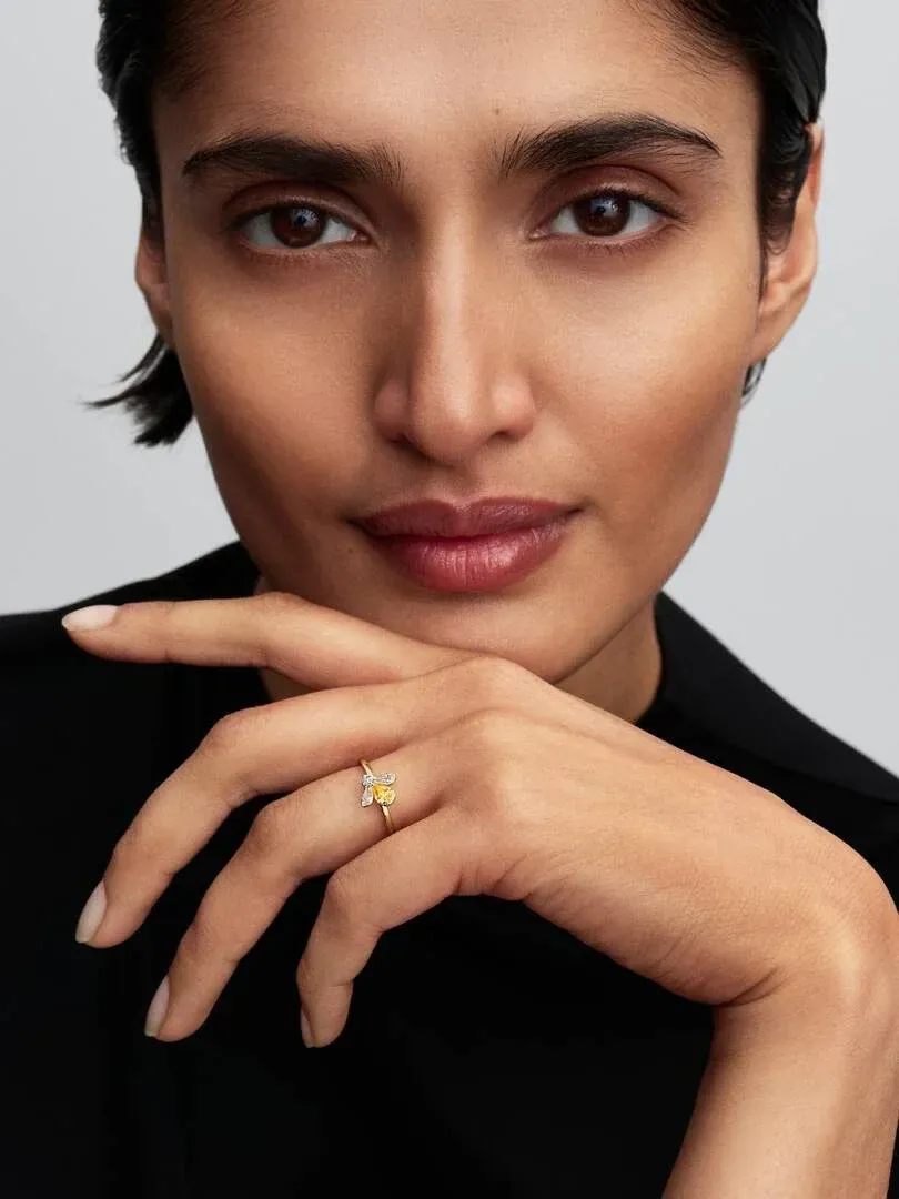 Nahaufnahme einer Hand am Kinn, die den Ring mit dem gelben Bienenmotiv zeigt.