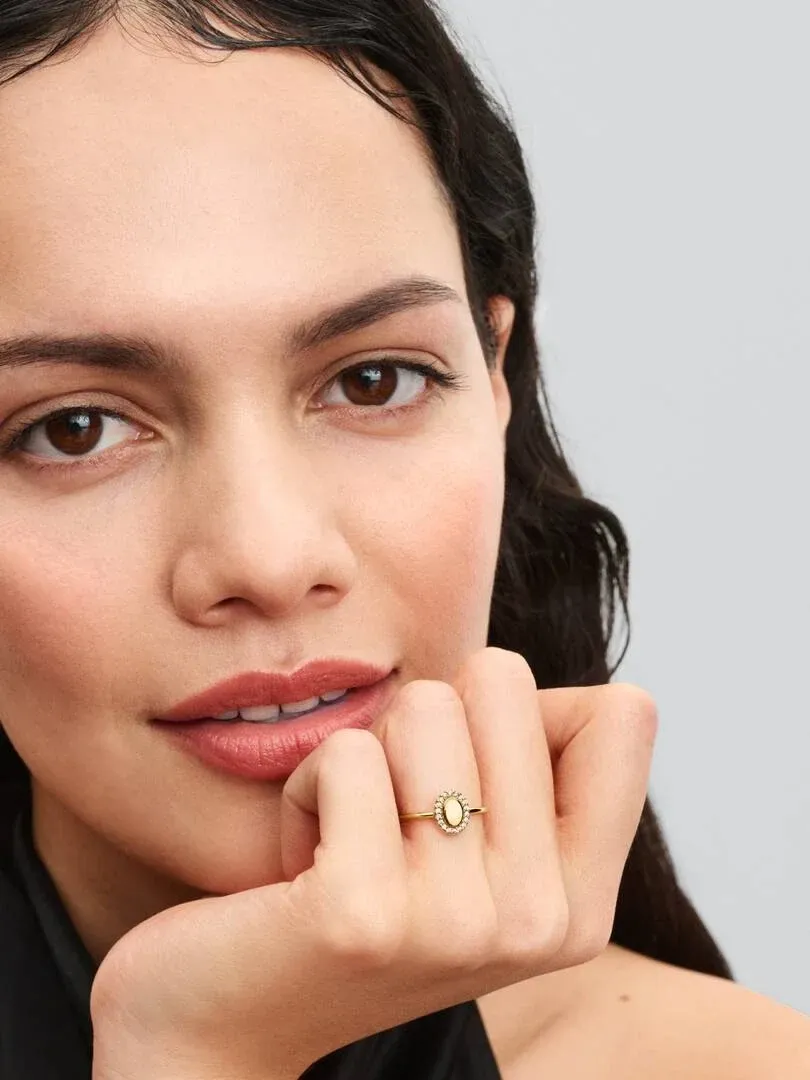 Nahaufnahme des ovalen Rings am Ringfinger, Model vor neutralem, unscharfem Hintergrund.