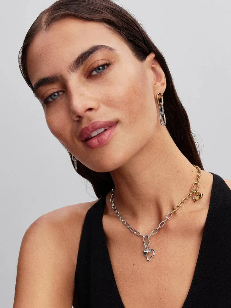 Nahaufnahme eines Models mit Gliederkette und passenden Ohrringen, Frontansicht vor neutralem Hintergrund.