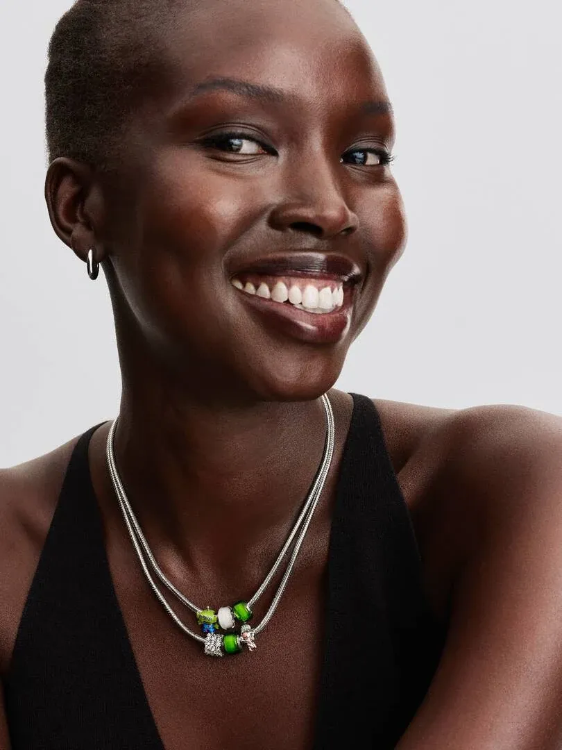 Close-up of necklace with Remy charm worn by model, front view against neutral grey background.