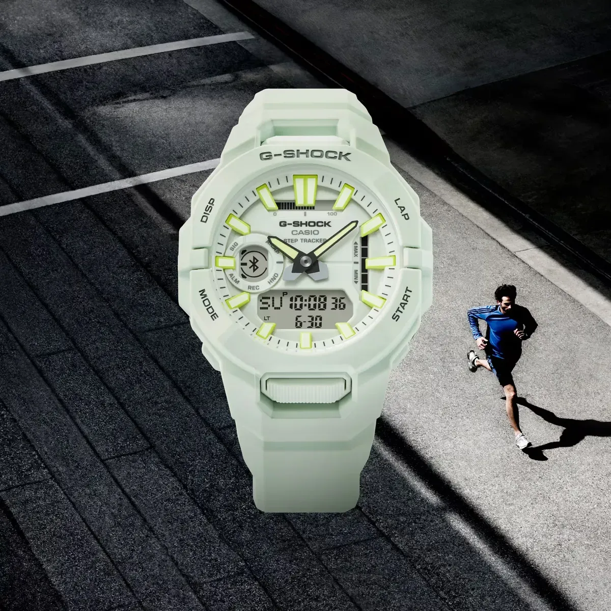 Reloj blanco visto frontalmente, superpuesto sobre una imagen de un hombre corriendo por una carretera de asfalto.