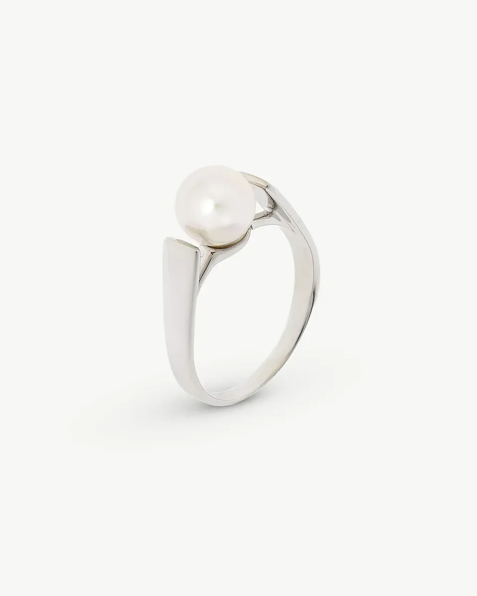 Anillo de plata con perla blanca, vista en ángulo tres cuartos sobre fondo blanco.