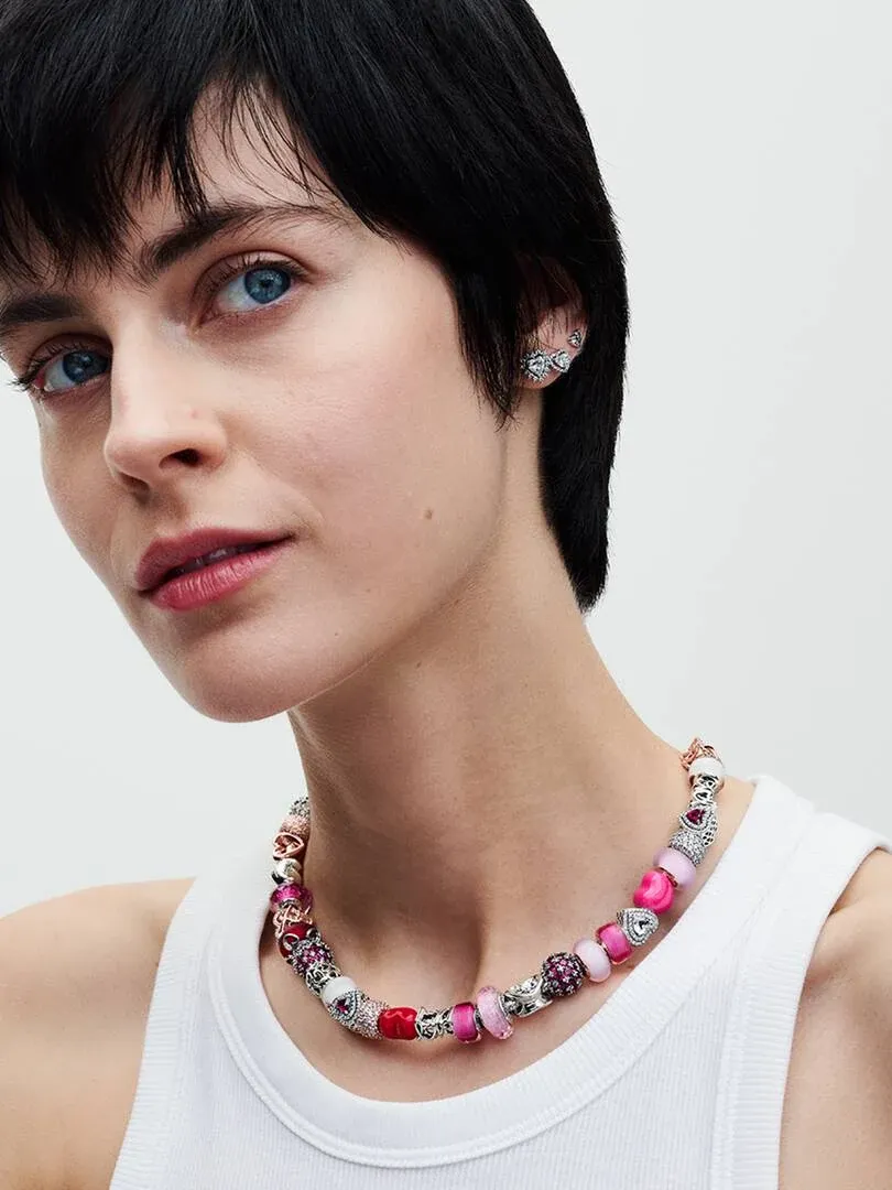 Close-up van een model met een kleurrijke charm-ketting, zijaanzicht gericht op de hals en sieraden.