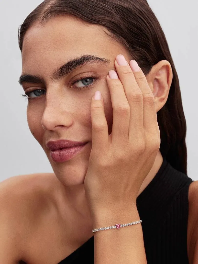 Close-up of the bracelet on the wrist, side view with model resting her face on her hand.