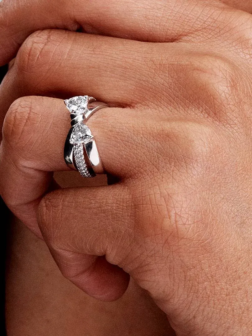 Close-up van de gekruiste bandring met zirkonia gedragen aan een vinger, zijaanzicht op de huid.