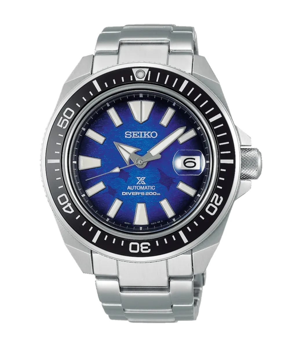 Vista frontal del reloj, esfera azul con motivo texturizado, bisel rotatorio negro y brazalete de acero, fondo blanco.