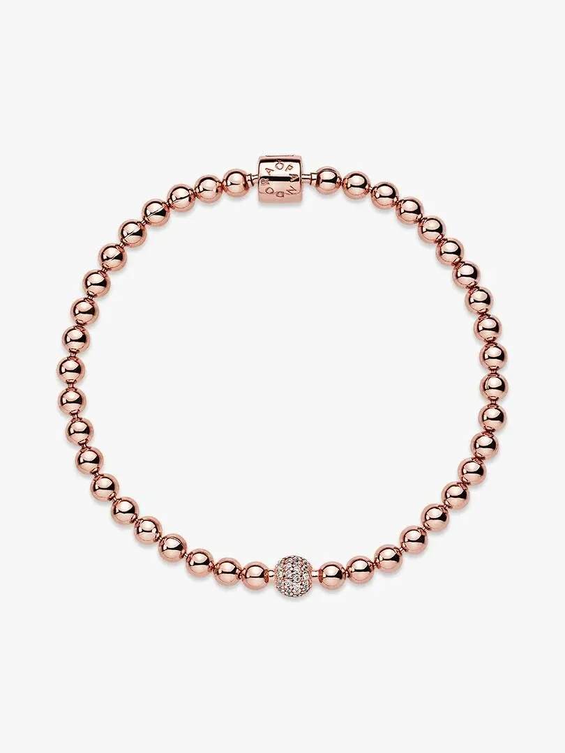 Draufsicht auf ein Perlenarmband aus Roségold in kreisförmiger Anordnung auf weißem Hintergrund.