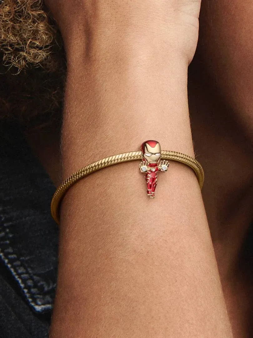 Nahaufnahme des goldenen Armbands mit dem Iron Man Charm am Handgelenk, Seitenansicht vor unscharfem Hintergrund.
