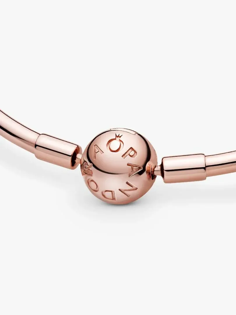 Gros plan du fermoir sphérique avec logo gravé, bracelet en or rose sur fond blanc.