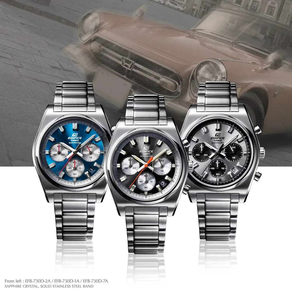 Tres relojes de diferentes colores de esfera alineados sobre fondo blanco reflectante y fondo superior de coche clásico.