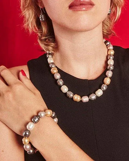 Primer plano de collar y pulsera de perlas barrocas sobre modelo con vestido negro y fondo rojo vibrante.