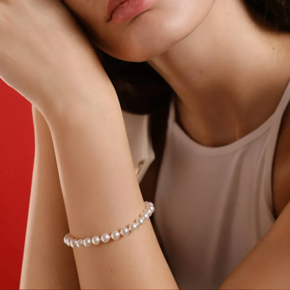 Close-up of the pearl bracelet on a wrist, side view against a vibrant red background.