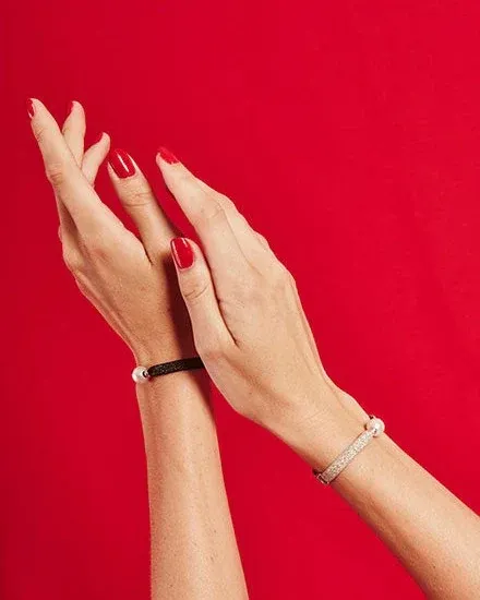 Close-up van twee polsen met armbanden tegen een levendige rode achtergrond, zijaanzicht.