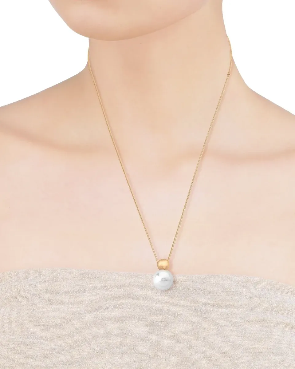 Primer plano del collar con perla blanca sobre el cuello de una modelo, toma frontal centrada.