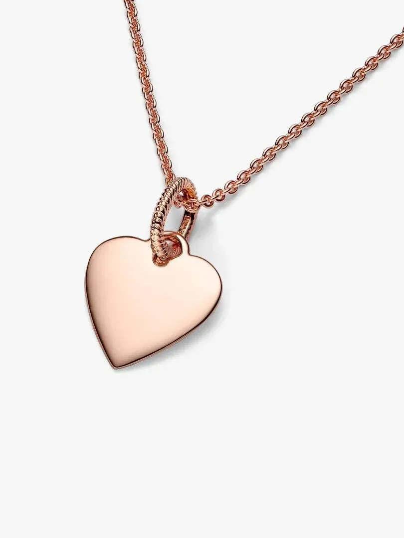Pendentif cœur en or rose sur fond blanc, vue de face avec détail de la chaîne.