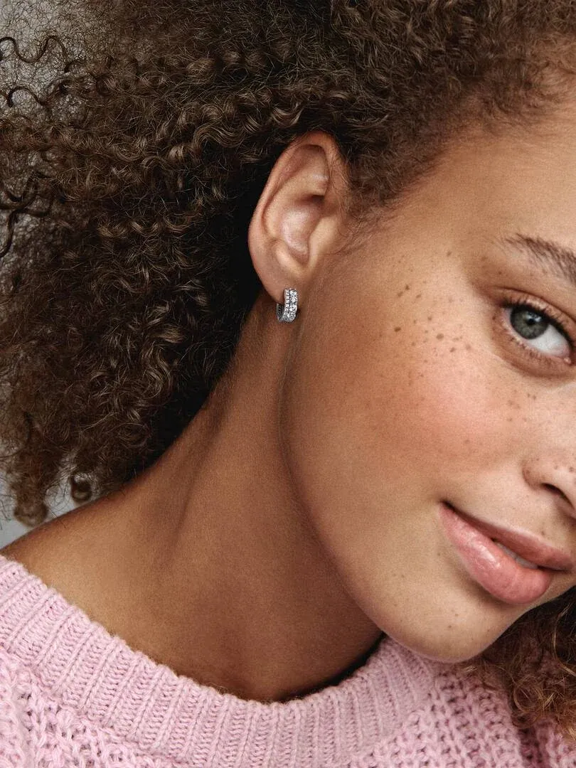 Zijaanzicht close-up van een dubbele band pavé oorring gedragen door een model, wazige achtergrond.