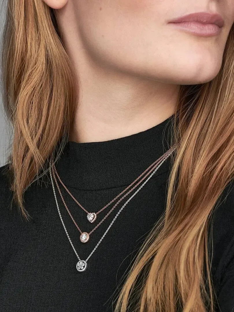 Primer plano de collar con colgantes de corazón sobre cuello y prenda negra, toma frontal.