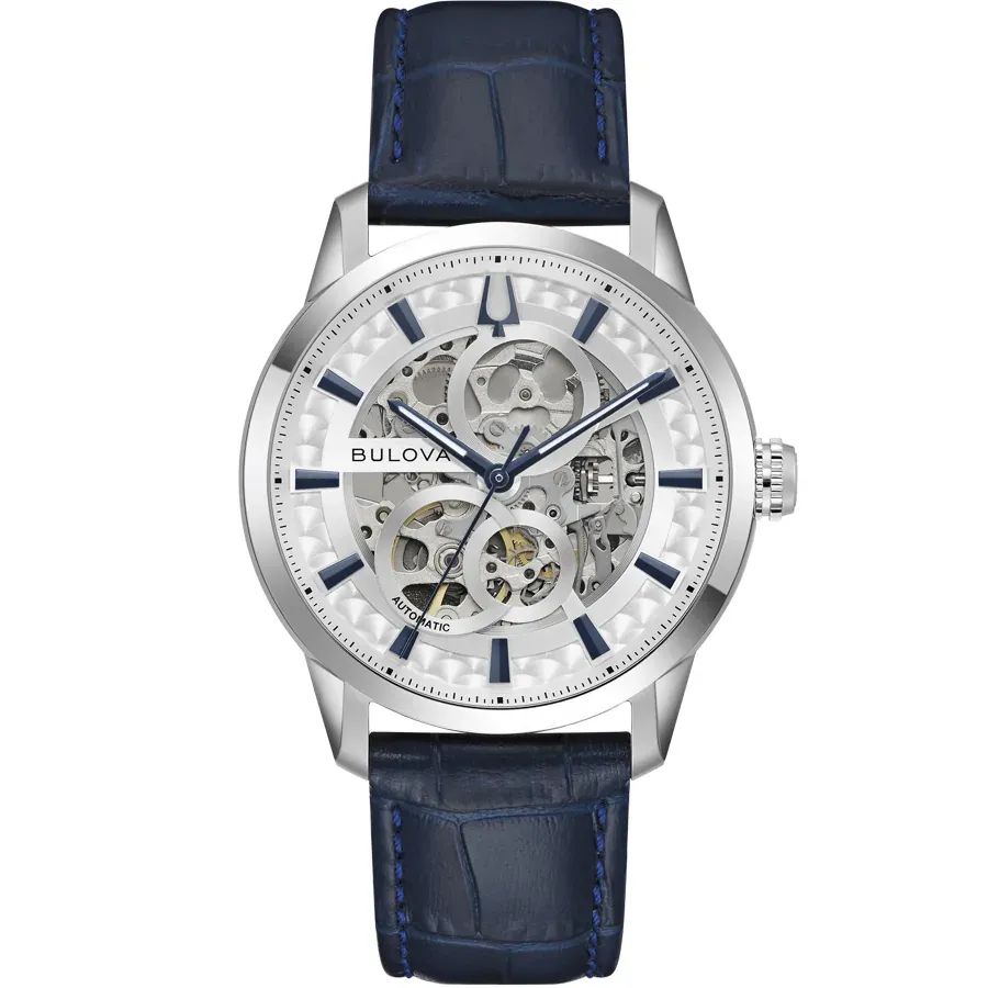 Reloj de pulsera visto de frente sobre fondo blanco, esfera skeleton y correa de piel azul.